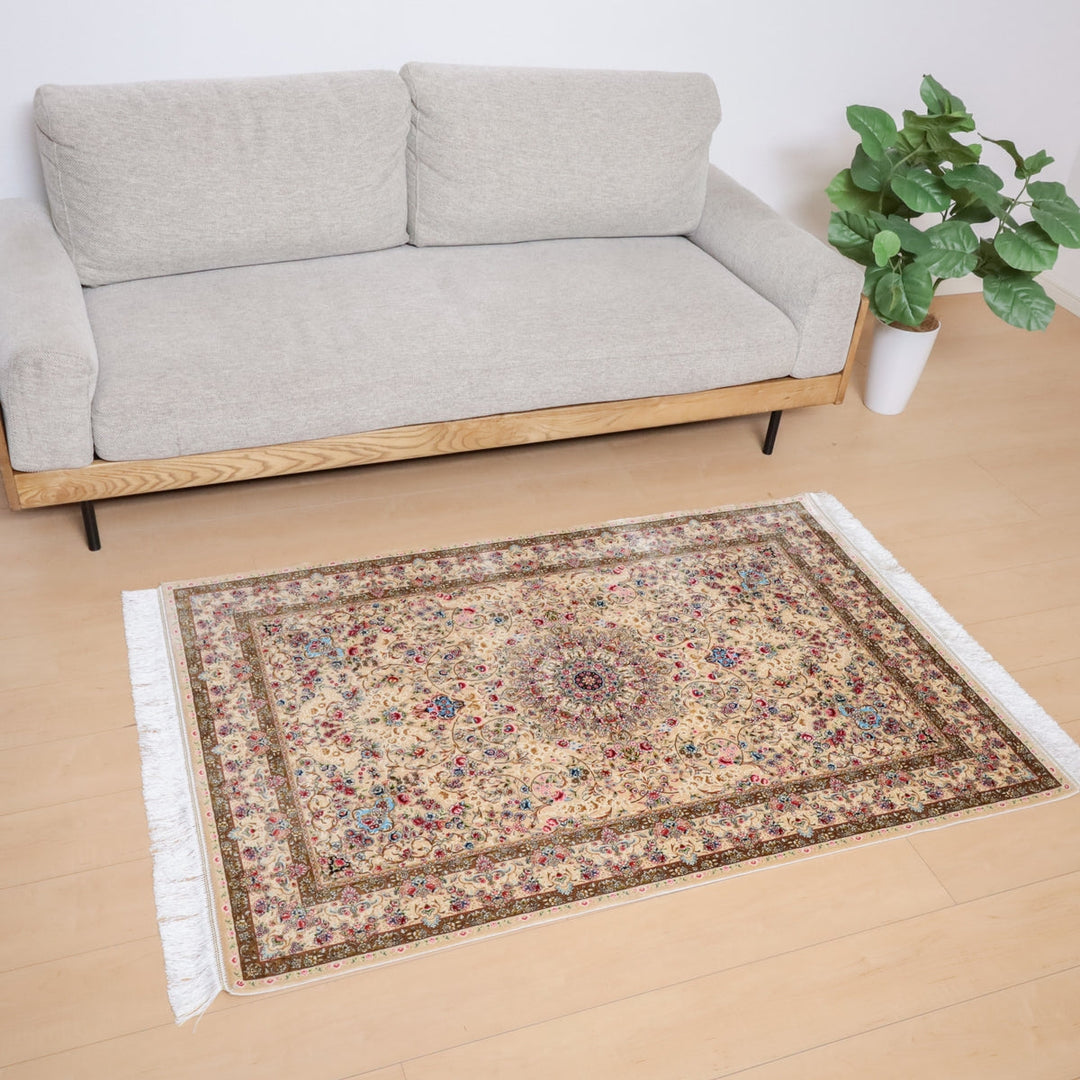 ラティーフカーペット LATIF 極密シリーズ (S-113)は、ベージュのソファの前に華やかな模様が施された手織りのペルシャ絨毯が敷かれ、ウールの温かみがリビングに落ち着きを与えている様子が見える。