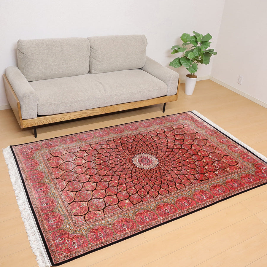 ラティーフカーペット LATIF 極密シリーズ (S-114)は、グレーのソファ前に敷かれたペルシャ絨毯専門店の赤いギャッベラグが、手織りのぬくもりとウールの華やかさをリビングに加えている。