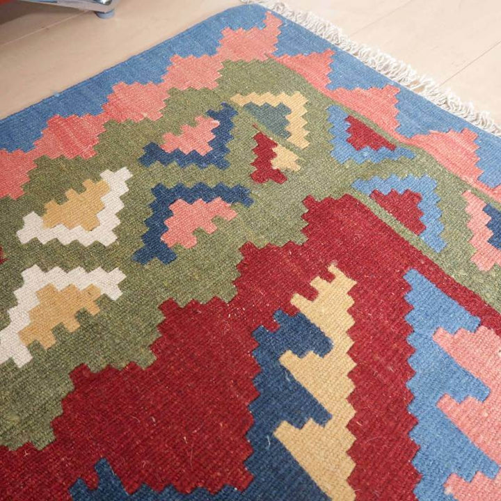 色鮮やかな模様が印象的な手織りウールのギャッベラグが、リビングの床に敷かれている。
