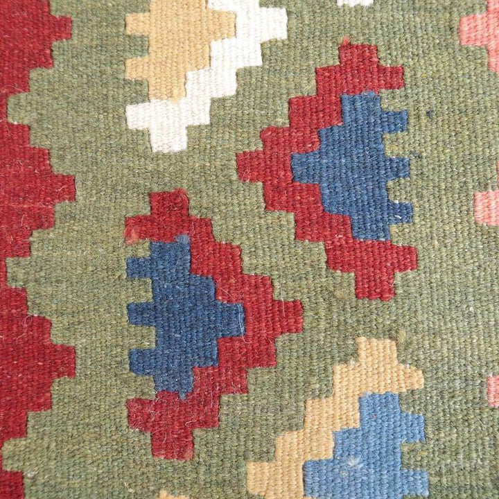 緑を基調に赤や青の幾何学模様が描かれた手織りのギャッベラグが、ペルシャ絨毯専門店の通販で見つかる。