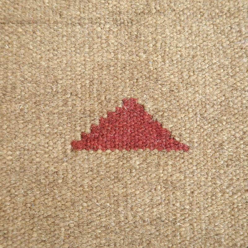 暖かみのあるウール素材に手織りで施された赤い三角模様が印象的なギャッベラグが見える。