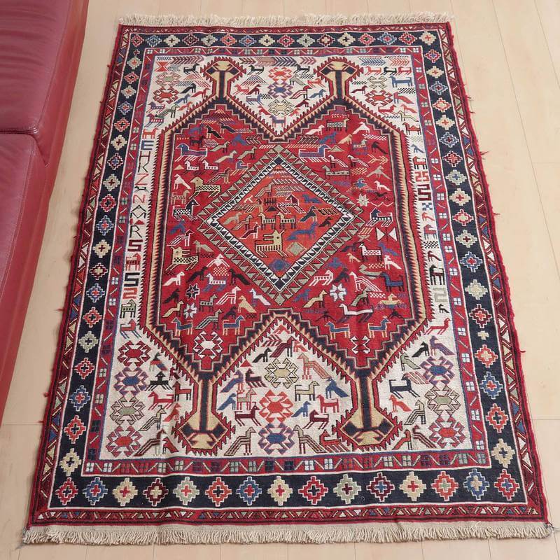 キリム・アゼルバイジャン 192×120cm(KL-29)は、赤と青の幾何学模様が印象的な手織りのギャッベラグが、明るい木の床に敷かれている。