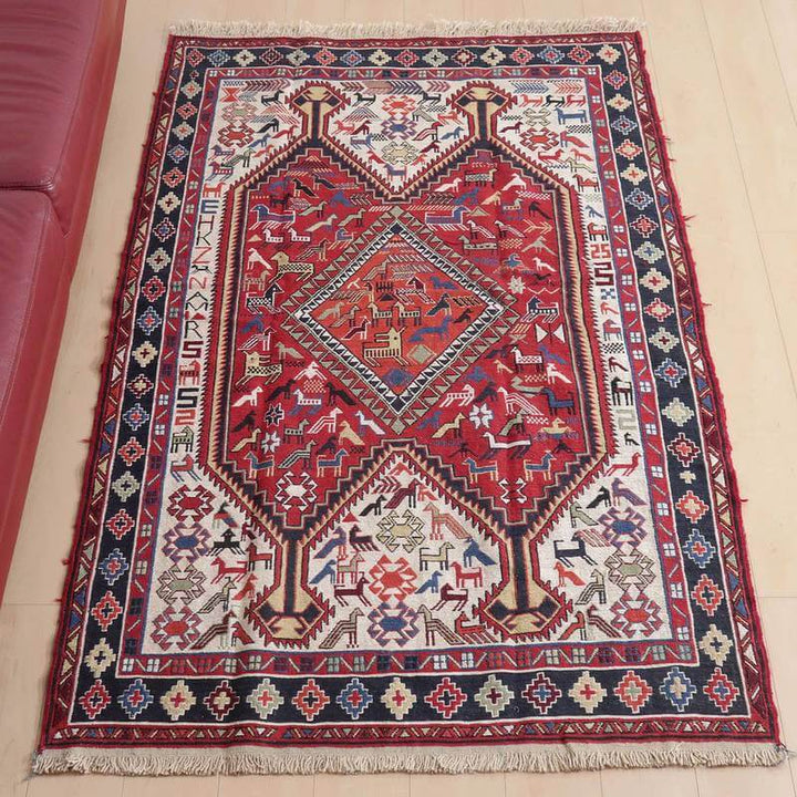 キリム・アゼルバイジャン 192×120cm(KL-29)は、赤と青の幾何学模様が印象的な手織りのギャッベラグが、明るい木の床に敷かれている。