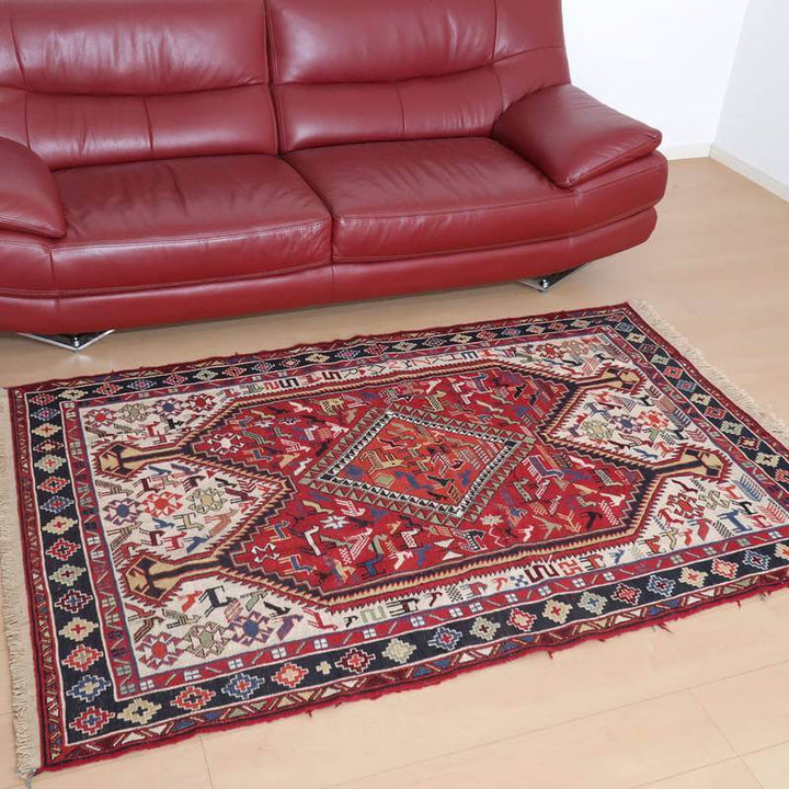赤いソファの前に広がるペルシャ絨毯風のギャッベラグは、手織りのウール素材が醸し出すぬくもりと大胆な模様がリビングの床に映えている。