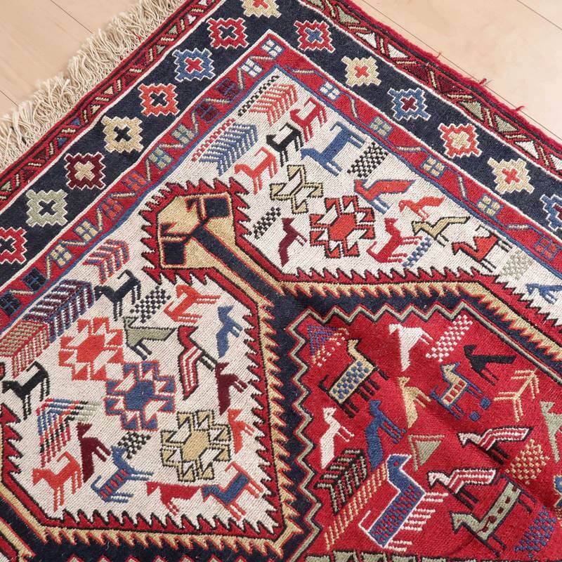 色彩豊かな幾何学模様が特徴的なギャッベラグが床に広がり、手織りウールの風合いとペルシャ絨毯の伝統が際立っています。