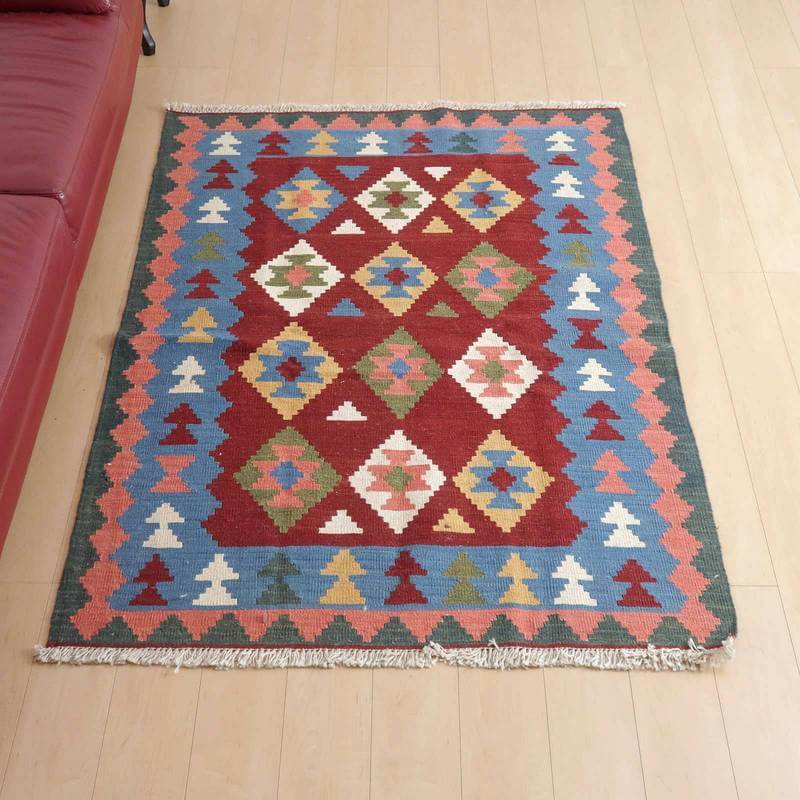 キリム・シラーズ/カシュガイ 174×125cm(KL-400)は、色鮮やかなジオメトリック模様が特徴のギャッベラグが、リビングの床にしっかりと敷かれている。