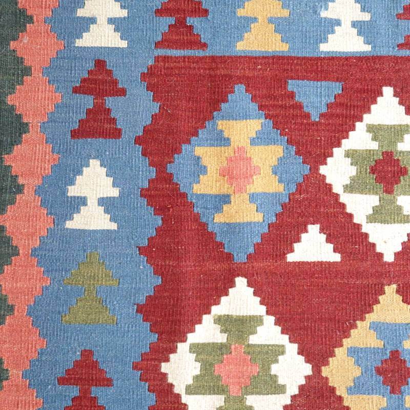 色鮮やかな幾何学模様が特徴の手織りギャッベラグが床に広がり、ウール素材の温かみが感じられる。