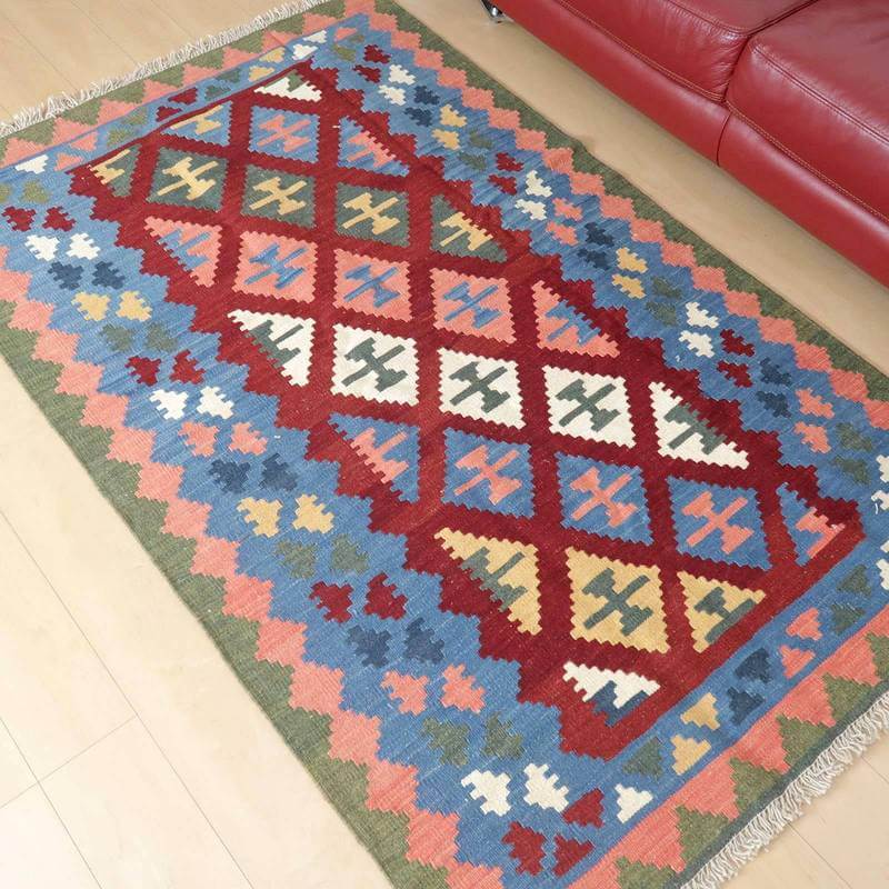 色鮮やかな幾何学模様が特徴の手織りウールギャッベラグが、リビングの床に敷かれている。
