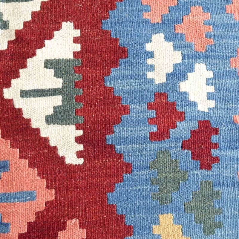 手織りのギャッベラグが、鮮やかな赤と青の幾何学模様で織り込まれたウールの質感豊かに映えている。