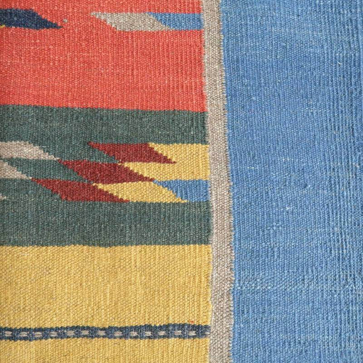 手織りのギャッベラグが、赤や青、黄色の幾何学模様で織り込まれたウールの風合いが際立っている。