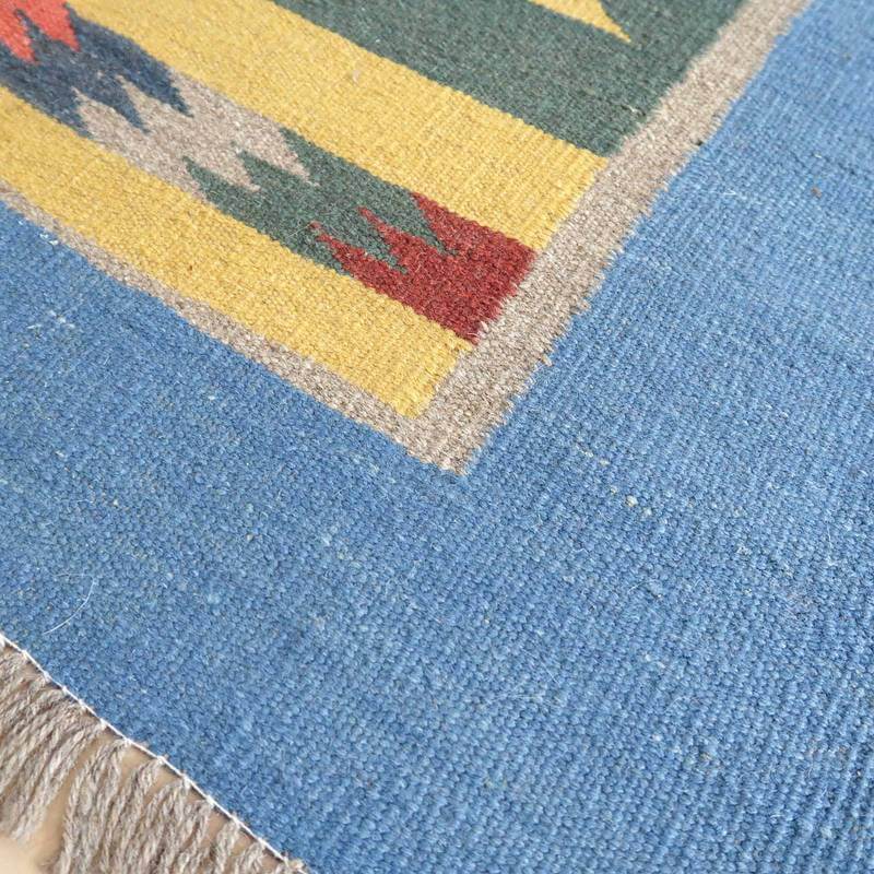 青い背景にカラフルな模様が施された手織りウールのギャッベラグが広がり、ペルシャ絨毯の専門店らしいぬくもりが感じられる。