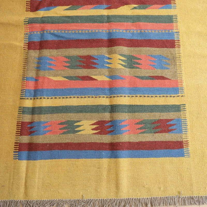 カラフルな模様と温かみのある色彩が特徴の手織りギャッベラグが床に広がり、ウール素材の柔らかさが際立っている。