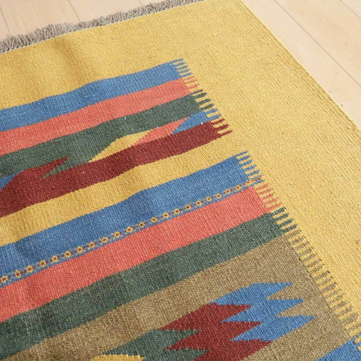 鮮やかな色合いと幾何学模様が印象的なペルシャ絨毯のギャッベが、手織りウールの質感とともに床に映えている。