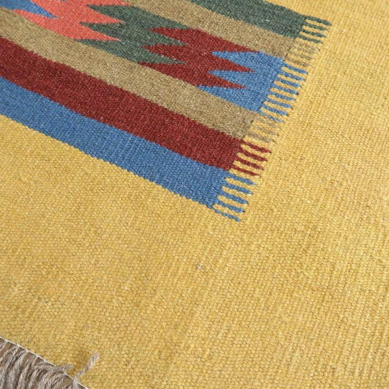 明るい黄色を背景に、手織りのギャッベラグがペルシャ絨毯専門店の通販で販売されており、幾何学模様の色合いが豊かに際立っている。