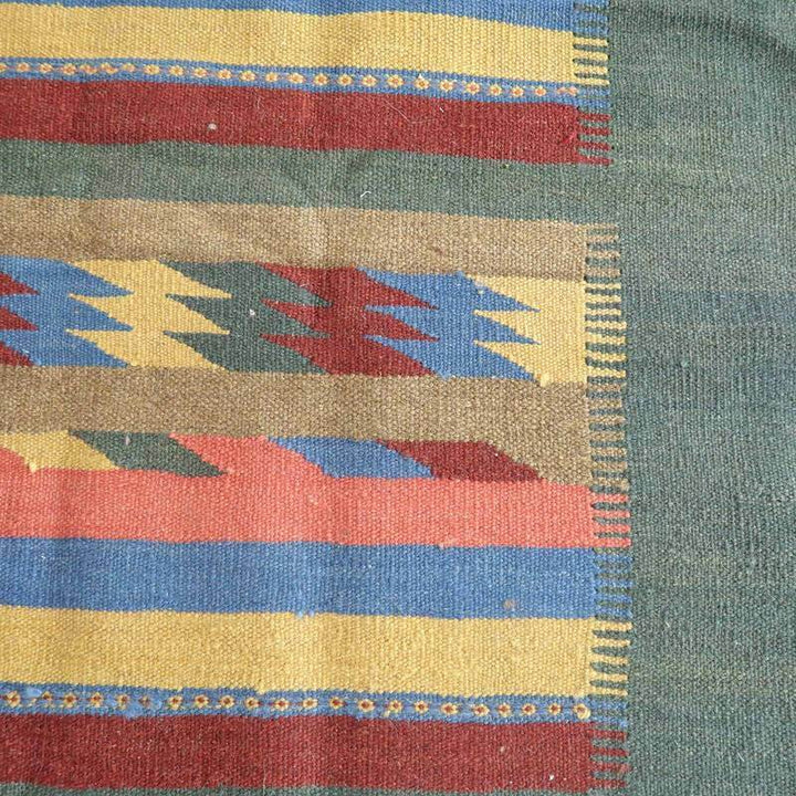 カラフルなジグザグ模様が魅力的な手織りのウール製ギャッベラグが、落ち着いたペルシャ絨毯として専門店の通販で提供されています。