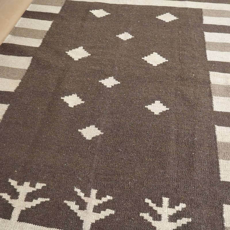 手織りで丁寧に作られたウールのギャッベラグは、温かみのあるブラウンの色合いに幾何学模様とペルシャ絨毯のデザインが魅力的に映えている。