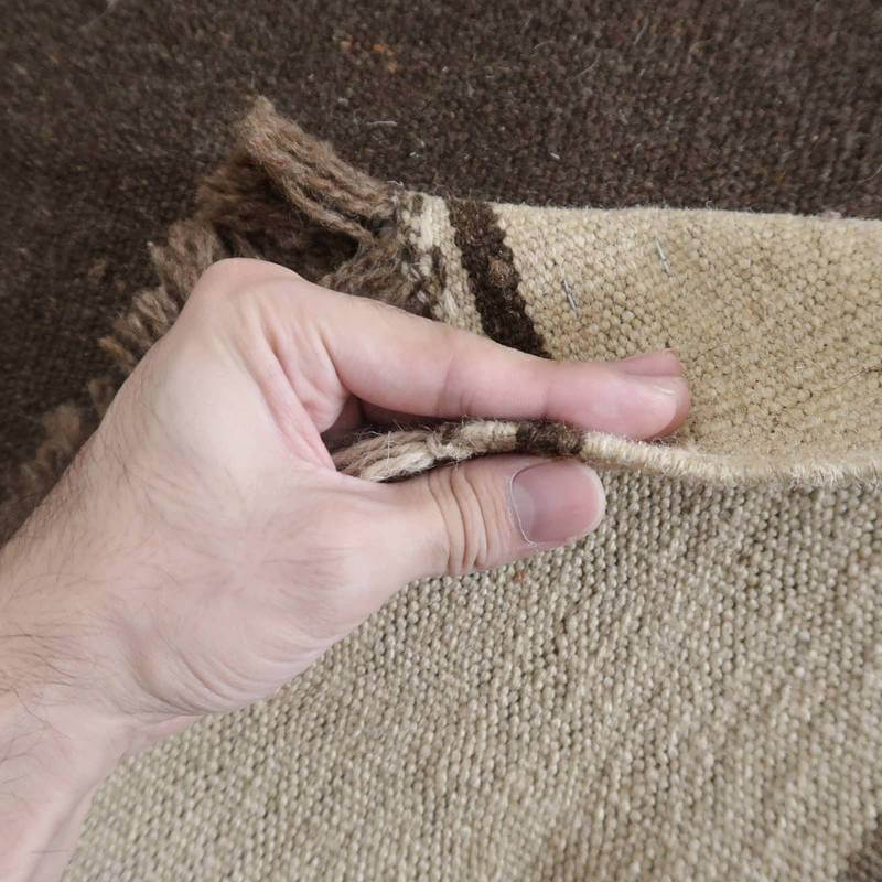 手織りの温もりを感じるウール素材のギャッベラグが丁寧にめくられて、その織り目が際立っている。