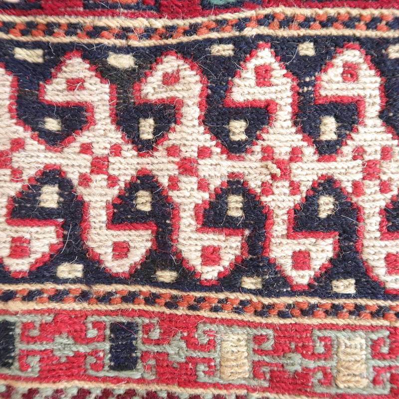 手織りのギャッベラグの接写で、赤と紺のペルシャ絨毯模様が丁寧に織り込まれたウールの質感が際立っています。