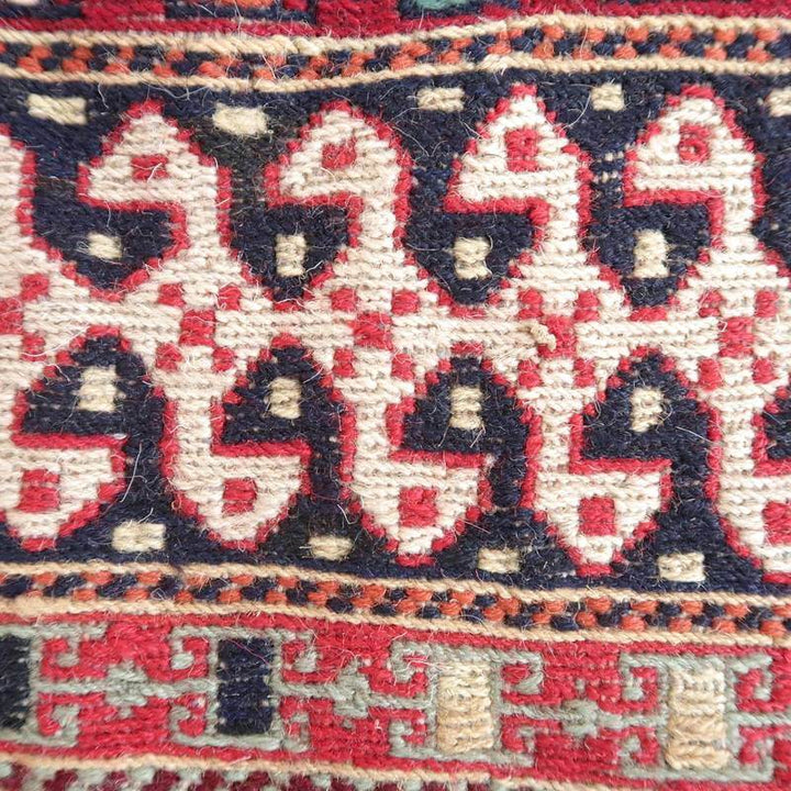 手織りのギャッベラグの接写で、赤と紺のペルシャ絨毯模様が丁寧に織り込まれたウールの質感が際立っています。