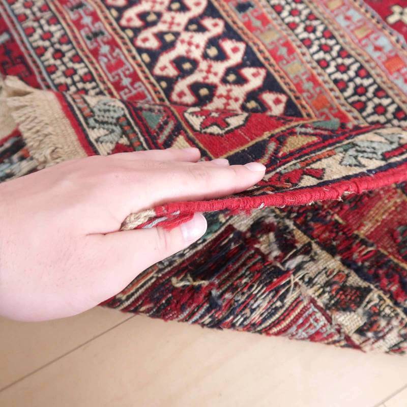 手織りのウール素材で丁寧に仕上げられたペルシャ絨毯のギャッベが、厚みのある織り目を際立たせながら床に柔らかくめくられている。