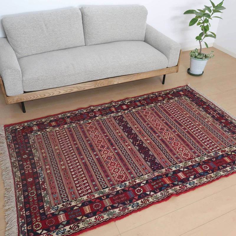 グレーのソファの前に敷かれた、色とりどりの模様が華やかなウール製手織りギャッベラグが、落ち着いたリビングに温かみを添えている。