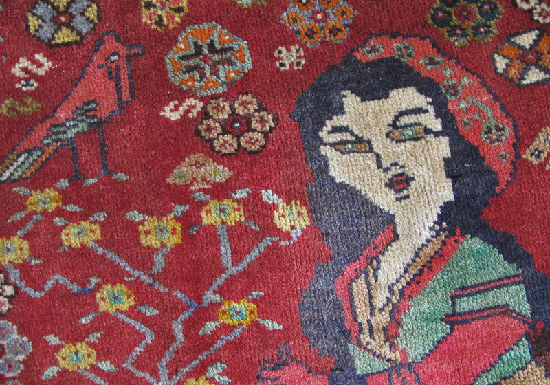 鮮やかな赤色を背景に、手織りのギャッベラグが見事にペルシャの伝統を描く一枚が広がり、精緻な模様と柔らかなウールの質感が際立っています。