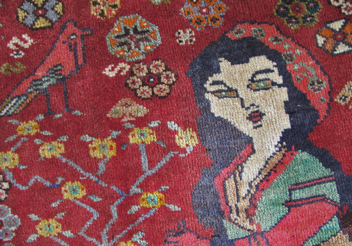 鮮やかな赤色を背景に、手織りのギャッベラグが見事にペルシャの伝統を描く一枚が広がり、精緻な模様と柔らかなウールの質感が際立っています。