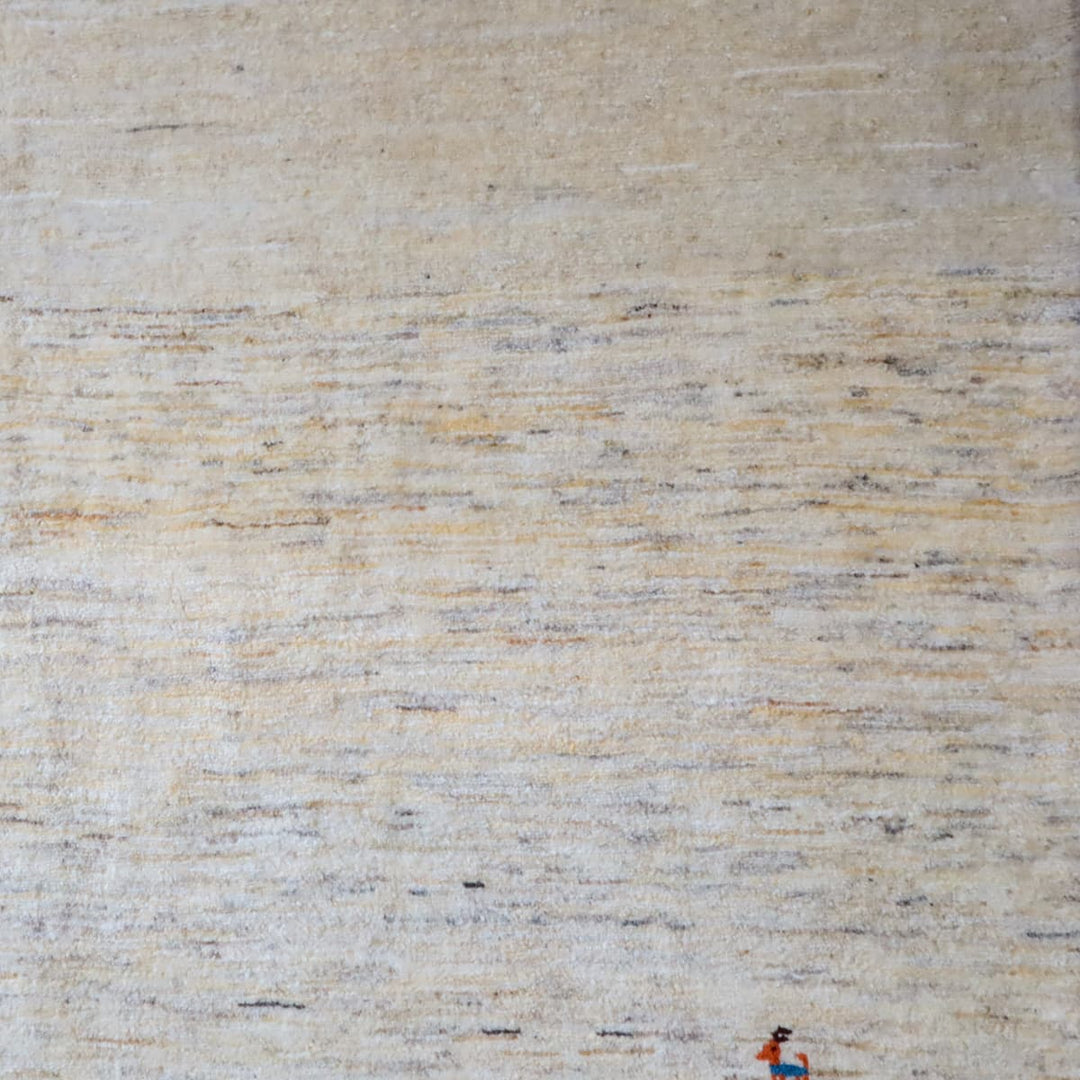 ギャッベHL-12947 角と房の写真 無染色ウールの羊色ベースに薄いグレーの揺らぎ、右下に小さな動物モチーフ Source