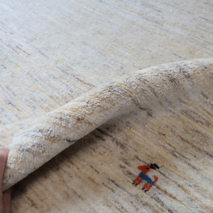 ギャッベHL-12947 毛足と厚みがわかる写真（端をめくった状態）柔らかなウールの手触り、動物モチーフ入り