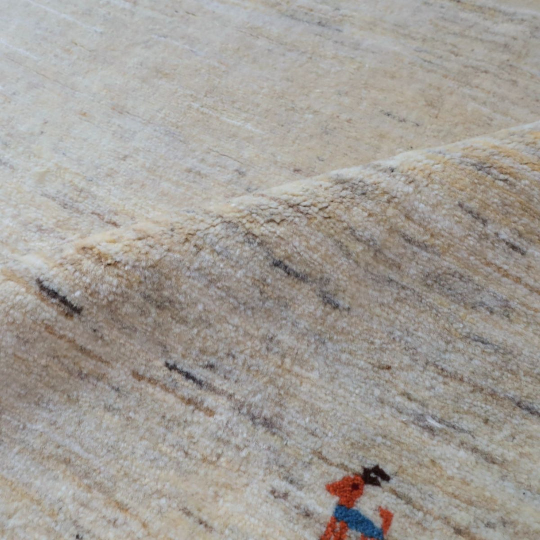 ギャッベHL-12947 表面の織り柄アップ 無染色ウールの羊色に薄いグレー・ベージュの筋感、ワンポイントの動物モチーフ