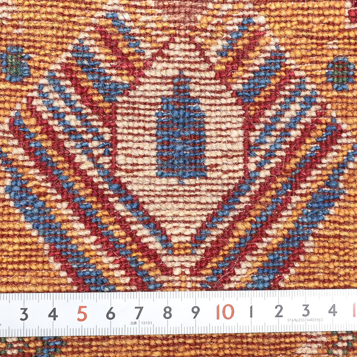 青と赤の幾何学模様が織り込まれた布の拡大写真、下にメジャーが置かれている