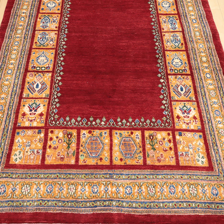 赤い中央部分と黄色の装飾的な縁取りがある伝統的な模様の織物敷物。