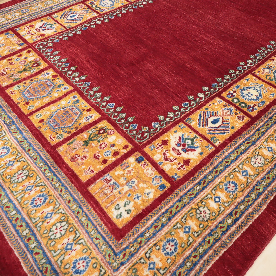 赤を基調とした中央部分と黄色と青の幾何学模様が縁取る伝統的な織物のカーペットの一部