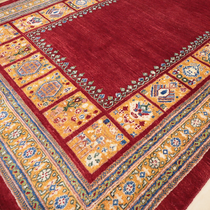 赤を基調とした中央部分と黄色と青の幾何学模様が縁取る伝統的な織物のカーペットの一部