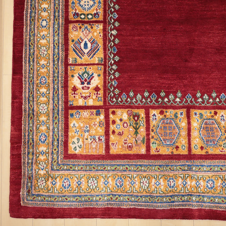 赤い中央部分と黄色の装飾縁取りがある伝統的な手織り絨毯の一部の詳細な写真