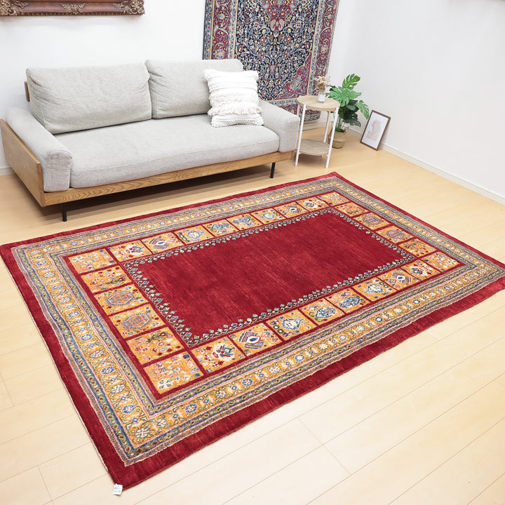 赤を基調とした伝統的なデザインの絨毯が置かれた明るいリビングルームの様子