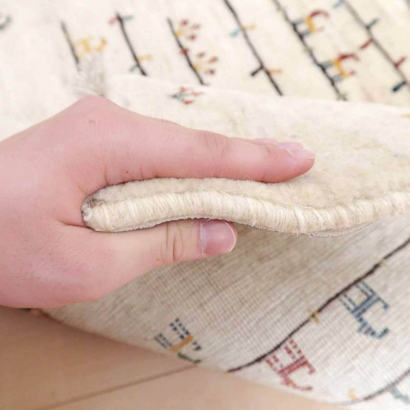 手触りの良い厚手のウールで丁寧に手織りされたギャッベラグが、持ち上げられた際にそのしっかりとした質感が際立っている。