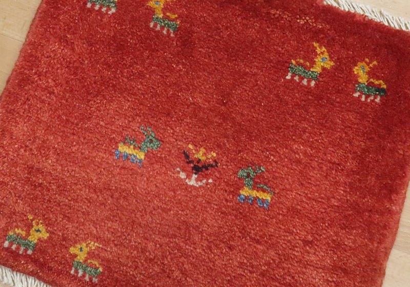 Rug with animal motifs in red, green and yellow — weave and texture