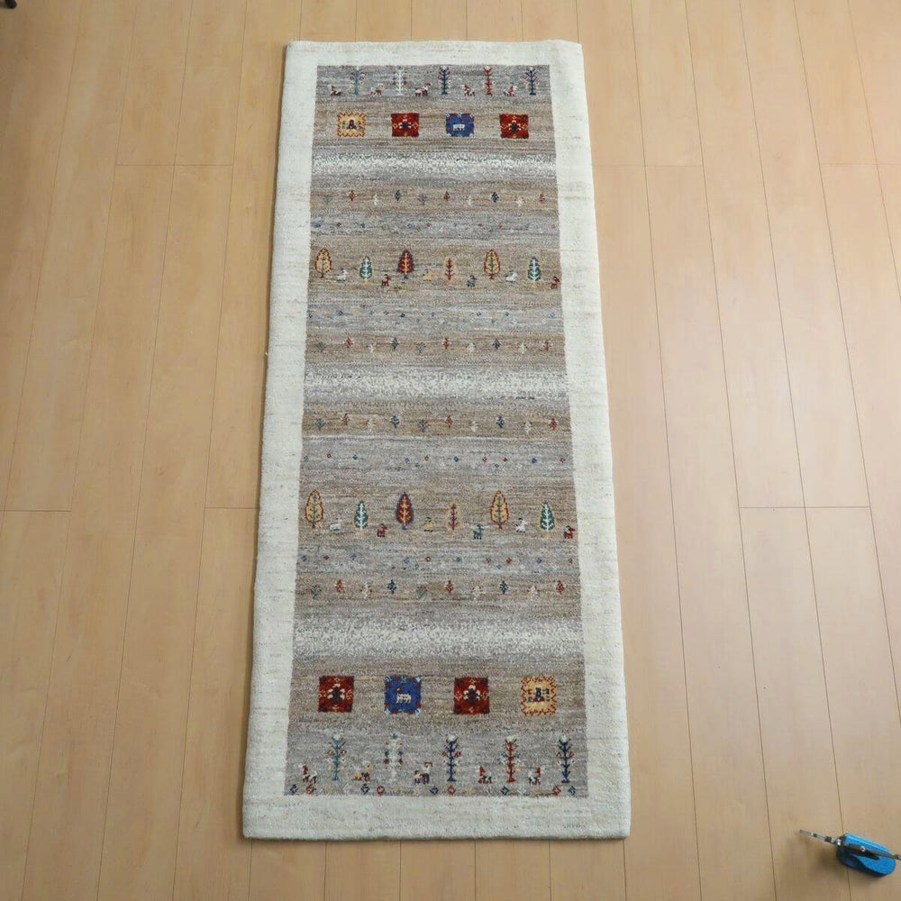 プレミアムギャッベ／ルリバフ 199×81cm（HR-11094）は、木目の床に優しく溶け込む、手織りのギャッベラグが敷かれていて、カラフルな模様がペルシャ絨毯の伝統を感じさせます。