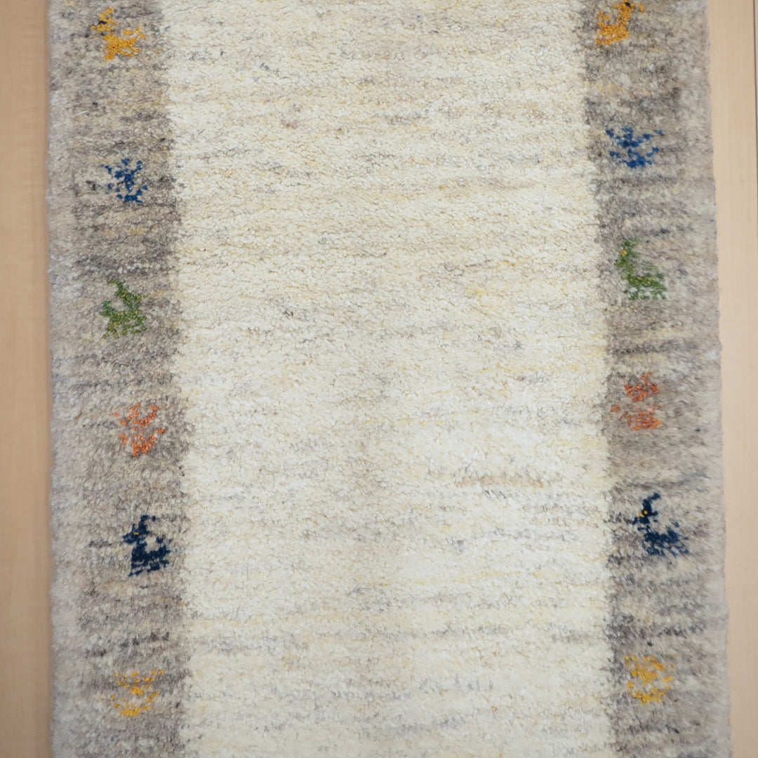 淡いグレーの縁にカラフルな小さな動物模様が配された、中央がクリーム色のラグマット。