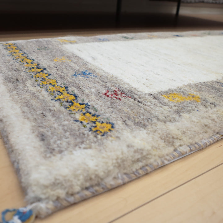 淡いグレーと白を基調とした織物の端が床に敷かれている様子が写っている画像