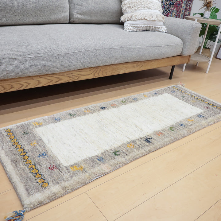 グレーのソファの前に敷かれた白とグレーを基調とした装飾的なラグがある室内の様子。