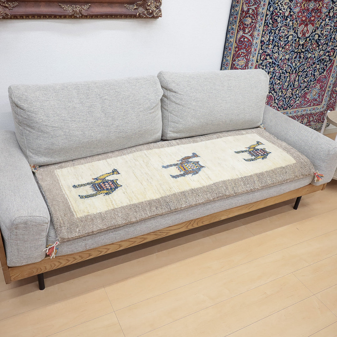 グレーのソファの前に敷かれた白とグレーを基調としたラクダのギャッベのある室内の様子。