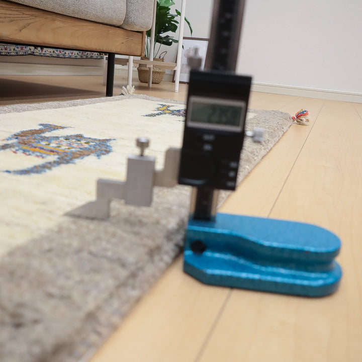 カーペットの厚みを測定するためにデジタルノギスが使用されている室内の様子