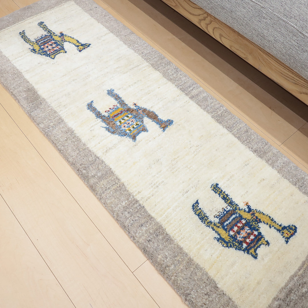 ベージュとグレーの縁取りがある長いラグに3体のカラフルな抽象的な動物の模様が並んでいる。