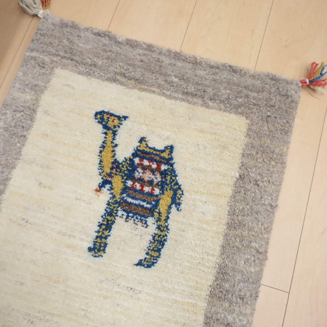 中央にカラフルなラクダの模様があるベージュとグレーのふんわりしたラグマット