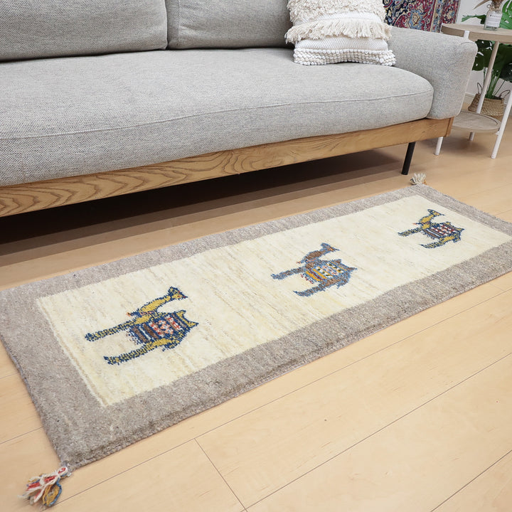 グレーのソファの前に敷かれた白とグレーを基調としたラクダのギャッベ