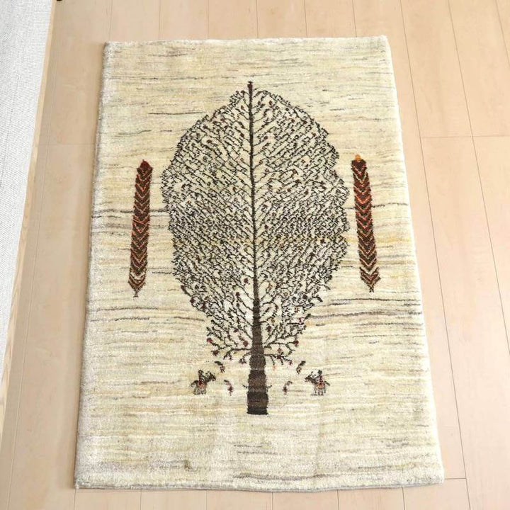 ギャッベ／カシュクリ 128×86cm（HS-75303）は、明るい木目の床に置かれた手織りのギャッベラグは、中央に大きな樹木のデザインが施され、自然のぬくもりが感じられる。