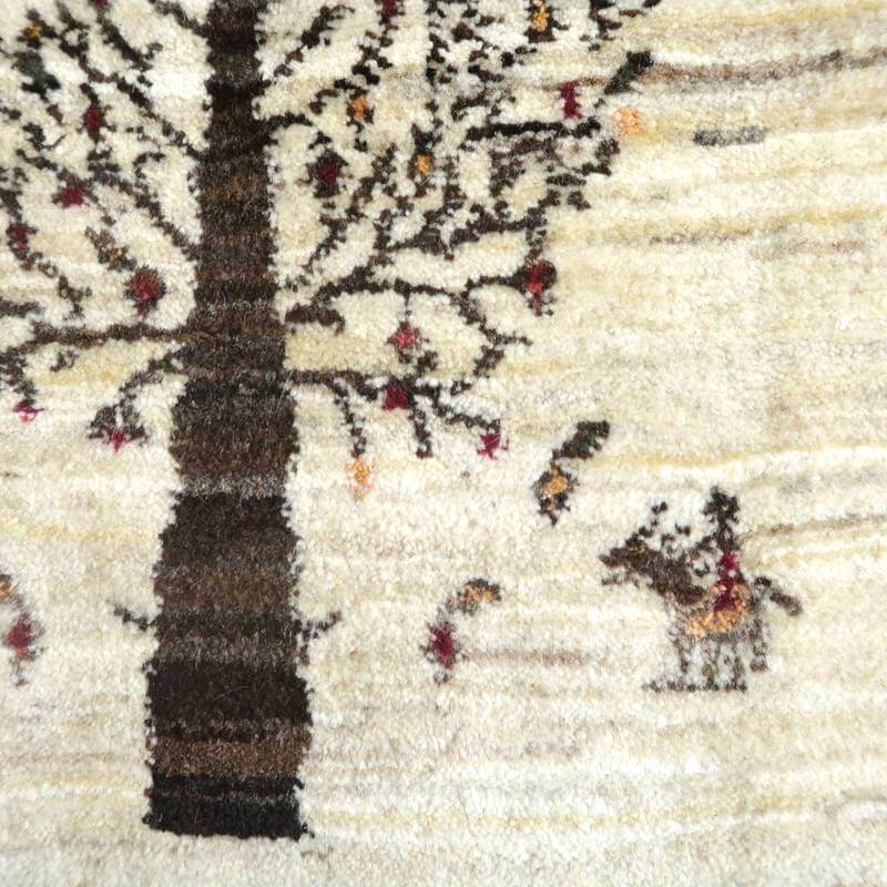 手織りのウール素材で丁寧に描かれた木と動物の模様が特徴的なギャッベのラグが、ペルシャ絨毯専門店の通販で見える。