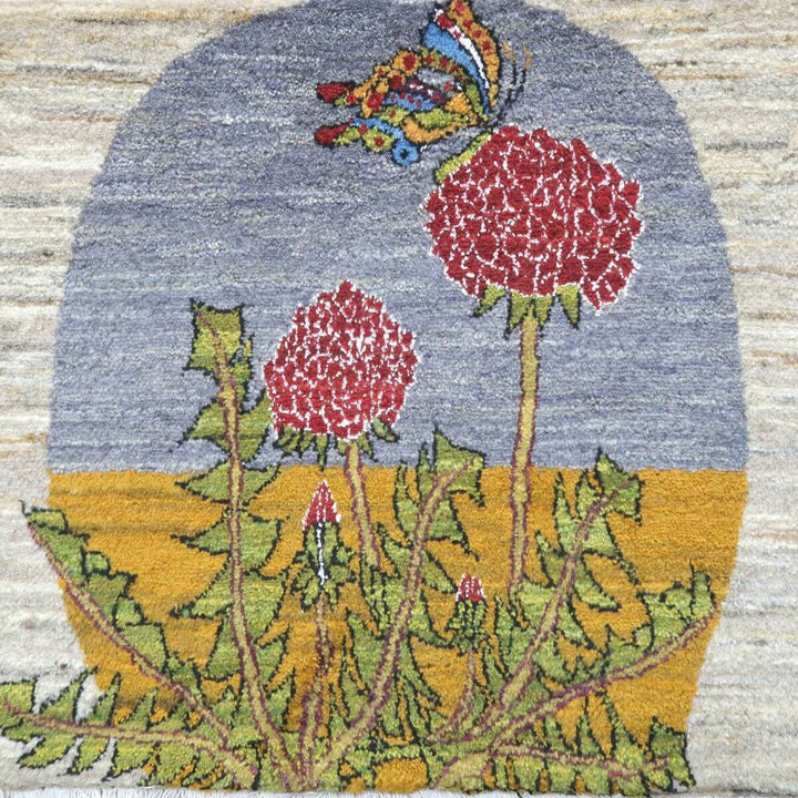 色鮮やかな蝶と花が描かれたペルシャ絨毯専門店の手織りウールラグが、自然のぬくもりを感じさせるデザインで床に広がっている。